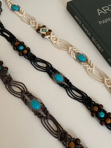 Detailed close-up of bohemian wax rope waist belts with wood beads and turquoise stones