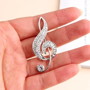 Close-up of a silver treble clef brooch with sparkling rhinestones held by hand