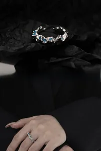 Macro detail of silver irregular wave ring featuring blue gemstones on black texture