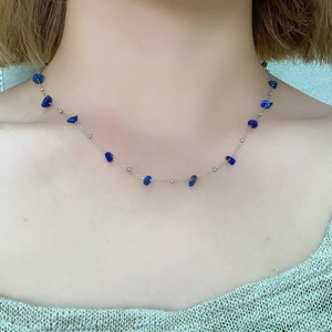 Close-up of minimalist silver necklace with blue irregular natural stone on model