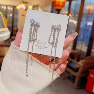 Détail de boucles d'oreilles étoile en argent avec pompons en strass et tige en argent 925