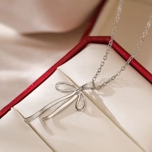 Minimalist silver ribbon bow pendant necklace displayed in a premium jewelry gift box