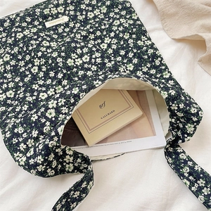 Floral canvas tote bag with daisy pattern and a magazine inside on a white bed sheet