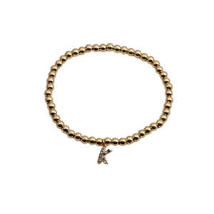 Macro view of golden bead bracelet featuring a colorful zircon-set letter K charm