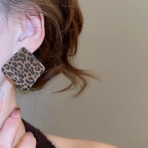Close-up of square leopard print earrings worn by model for a retro vintage style look