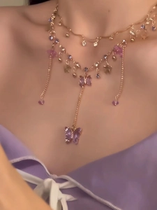 Close-up of double-layered necklace featuring butterfly and flower crystal pendants