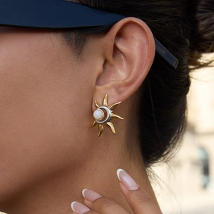 Macro view of gold sun stud earrings with white bead and silver crescent detail