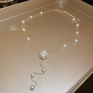 Détail du pendentif fleur de camélia doré avec perles blanches et zircons étincelants