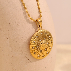 Detail of 18K gold compass star pendant with sun face and crystals on a ball chain
