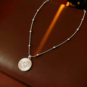 Minimalist silver daisy pendant necklace with pink zircon on brown leather background