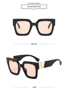 Detail of square black sunglasses with light tea lenses and gold metal W hinge accents