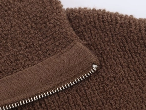 Close-up of the thick brown textured fabric and metal zipper of the bomber jacket