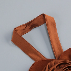 Detail of caramel satin halter dress featuring handmade 3D rose and elegant pleats