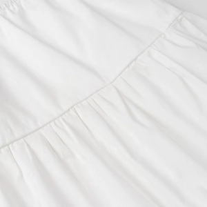 Macro view of white strapless top showing gathered fabric texture and stitching details