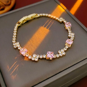 Luxurious gold tennis bracelet with pink square zircons and white crystals on box