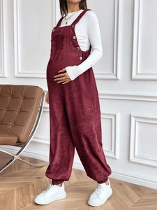 Detail of burgundy corduroy maternity overalls with adjustable waist and side buttons
