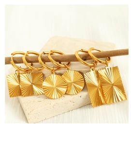 Close-up of 18K gold plated earrings with textured geometric shapes on a rustic background
