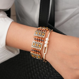 Detail showing vintage multi-layer bracelet with amber beads and pearl inlay on model wrist