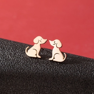 Macro shot of rose gold dog stud earrings on black leather with a red background