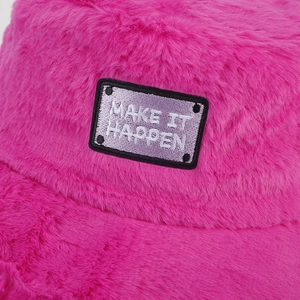 Détail du chapeau bob en peluche rose avec écusson MAKE IT HAPPEN et texture en fausse fourrure
