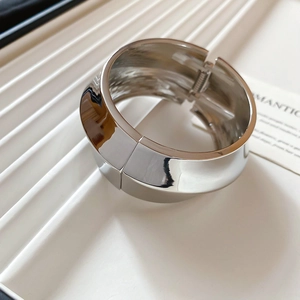 Detailed view of polished silver wavy bangle with high-gloss finish and hinge closure