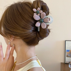 Dettaglio di un fermaglio per capelli in acrilico con fiori color malva sui capelli