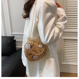 Detail of heart-shaped gold sequin evening bag with floral patterns and chain strap