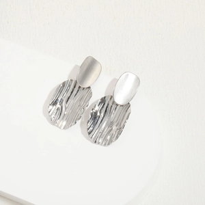 Detailed close-up of silver irregular wavy oval earrings with a modern metallic finish