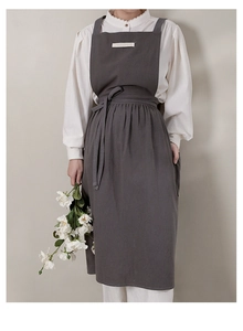 Detail of dark gray cotton apron with chest pocket and waist straps for kitchen