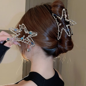 Détail de pinces à cheveux étoiles argentées avec gemmes bleues et roses sur un modèle