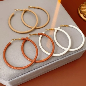 Detailed view of three pairs of geometric leather hoop earrings in brown and white