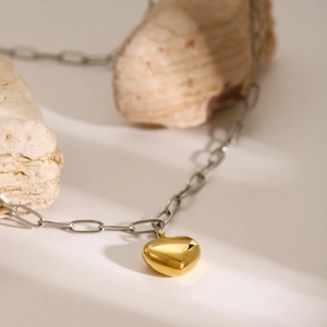 Macro detail of 18k gold heart pendant on silver paperclip chain with natural stone base