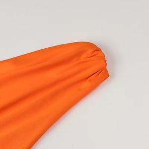 Gros plan sur le revers de manche orange vif en tissu polyester lisse et élastique