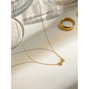 Detail shot of a delicate 18k gold plated stainless steel bow pendant necklace