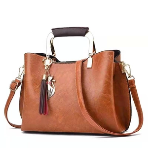 Chic brown PU leather handbag with metal handle and cat charm on white background