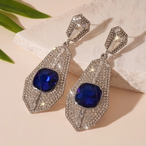 Macro detail of luxury geometric earrings with deep blue square stone and sparkling diamonds
