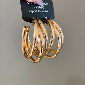 Detail shot of multi-layered gold hoop earrings with polished metal finish and card