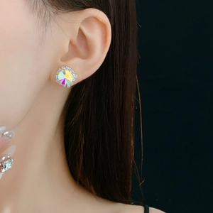 Close-up of sparkling colorful round crystal stud earring worn by a model on dark background