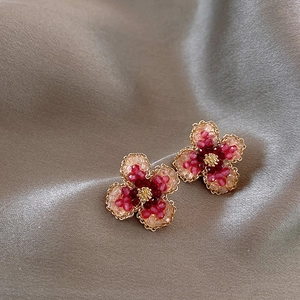 Detail of flower stud earrings with red gradient beads and golden metallic edges
