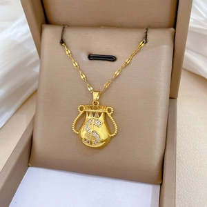 Close-up of golden money bag pendant necklace with $ sign and sparkling white zircons
