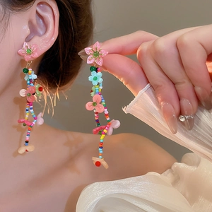 Gros plan de boucles d'oreilles pendantes à fleurs colorées au design de perles