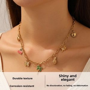 Close-up of gold-plated necklace featuring summer charms like cherry and palm tree on model