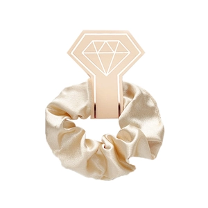 Detailed view of a champagne satin scrunchie with silk luster on a diamond display card