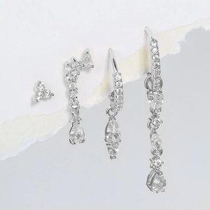 Detailed view of silver zircon earring set with teardrop pendants on torn paper