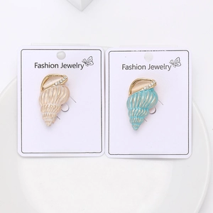 Detail of two gold enamel seashell brooches with rhinestones on a white ceramic tray