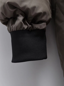 Close-up of olive windproof fabric sleeve with black ribbed knit storm cuffs detail