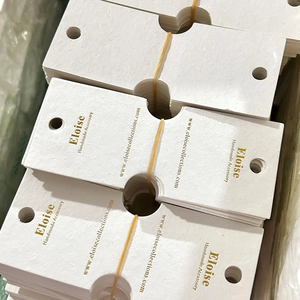 Detailed view of custom white textured jewelry cards with gold foil branding logo
