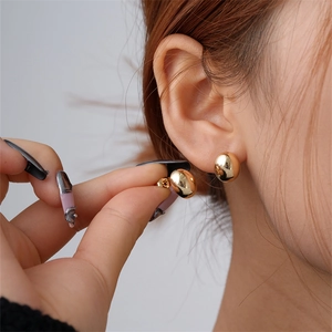 Macro close-up of shiny gold irregular pebble stud earrings on a model's ear