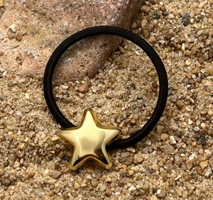 Close-up of a black elastic hair tie with a polished gold star charm on stones
