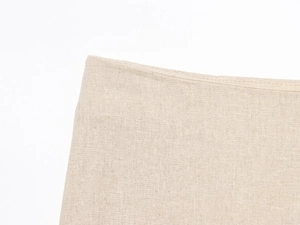 Détail rapproché du textile en lin beige montrant la texture du tissage et la couture